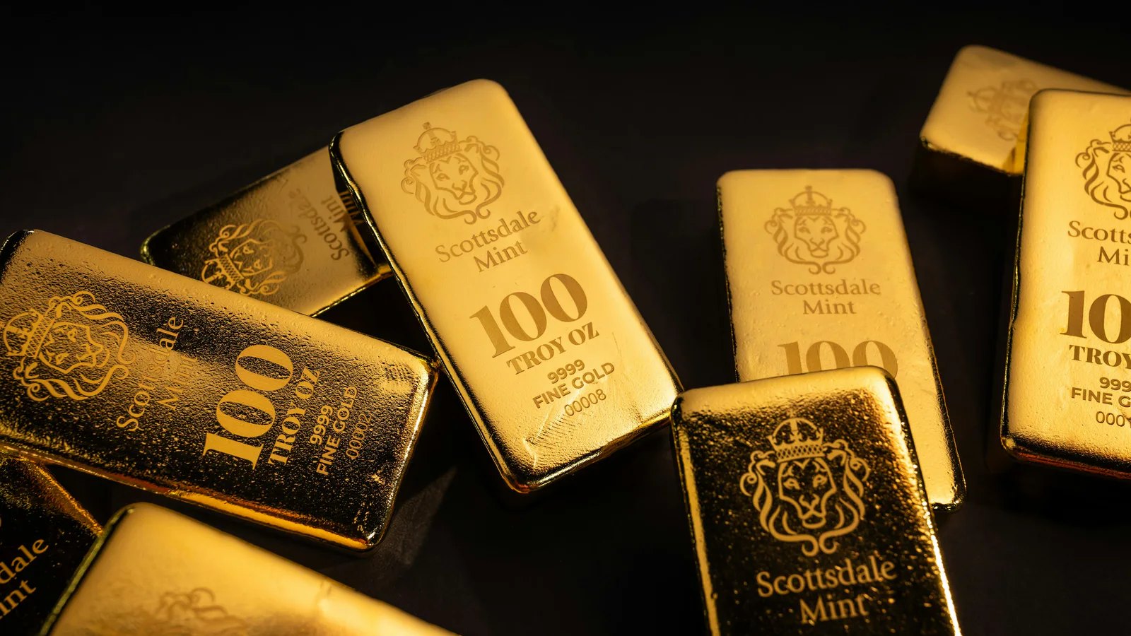 Scottsdale Mint gold bullion bars arranged on a dark surface